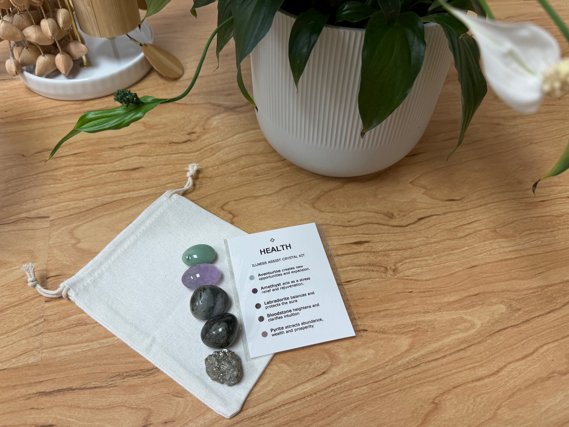 Set of chakra stones on a drawstring bag with a card next to it on a wooden surface.